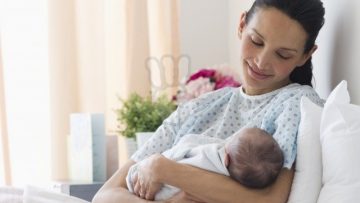 Mother holding newborn baby in hospital bed