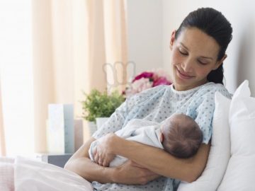 Mother holding newborn baby in hospital bed