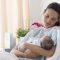 Mother holding newborn baby in hospital bed