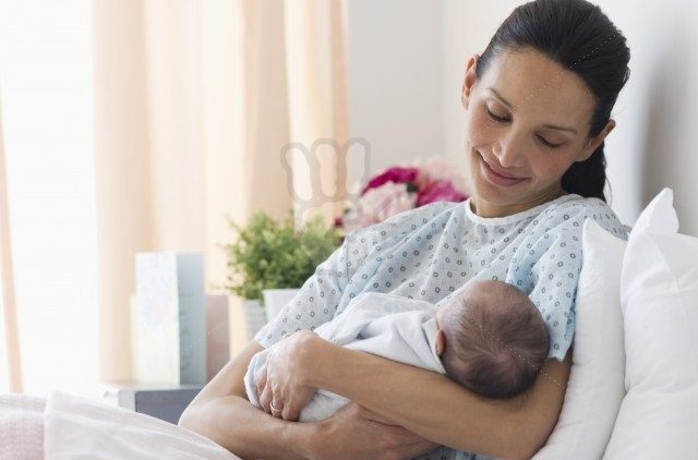 Mother holding newborn baby in hospital bed