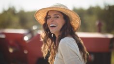 Portrait cheerful young woman wearing sun hat at farm