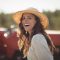 Portrait cheerful young woman wearing sun hat at farm